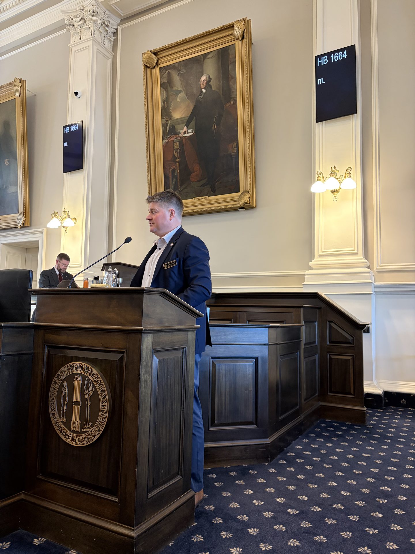 Greg Sargent speaking at the New Hampshire House podium